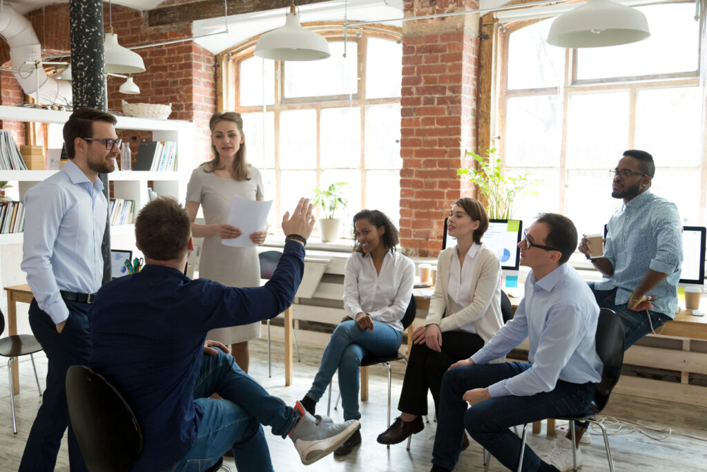 Mitarbeiter hebt die Hand und stellt eine Frage beim Teambuilding im Büro