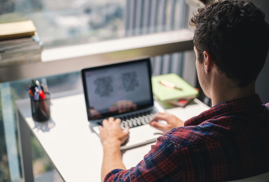 man tiping on a macbook in office