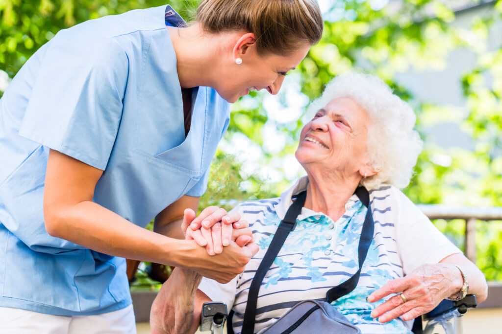 young nurse taking care of an old lady who is sitting and smiling