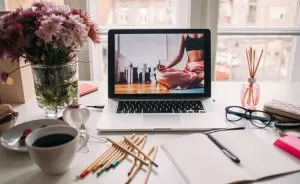 Macbook on a desk with flowers and pencils