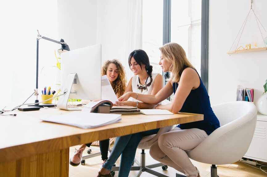 three female employees working together in the office at one desk