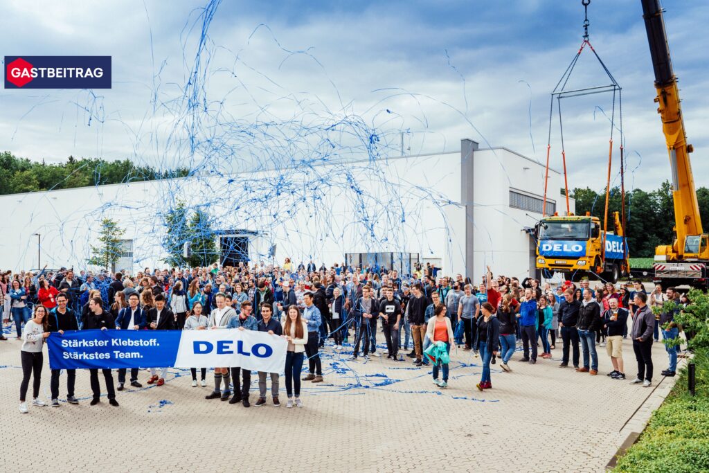 large group of employess standing outside holding up a sign