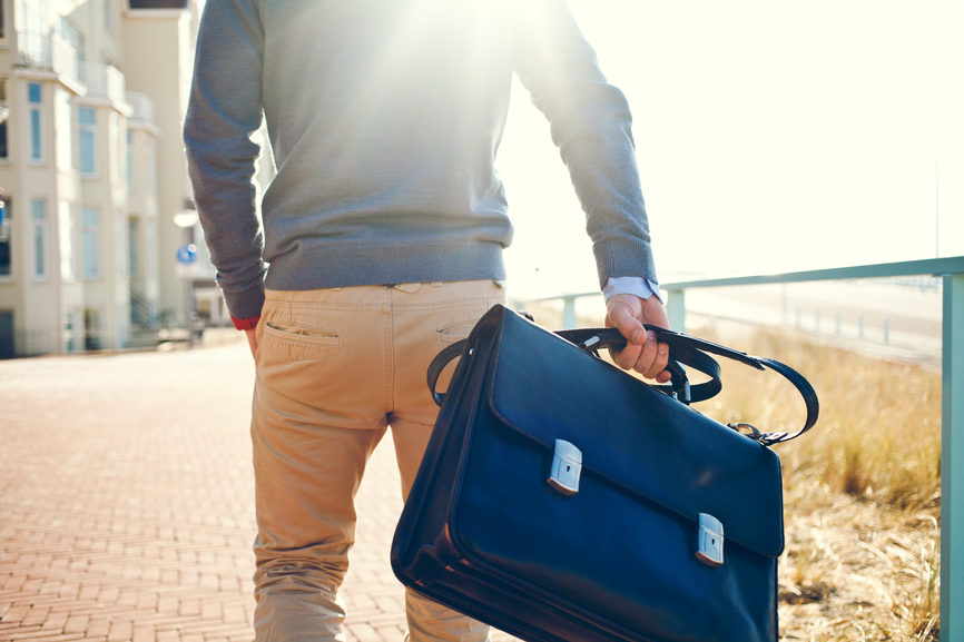 well dressed man holding a business bag behind his back