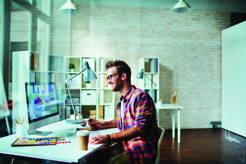 man sitting at a desk and working on a computer