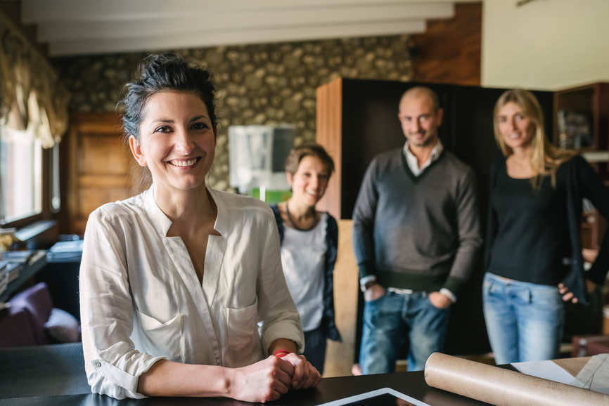 4 Personen im im Büro und Frau mit Bluse im Fokus