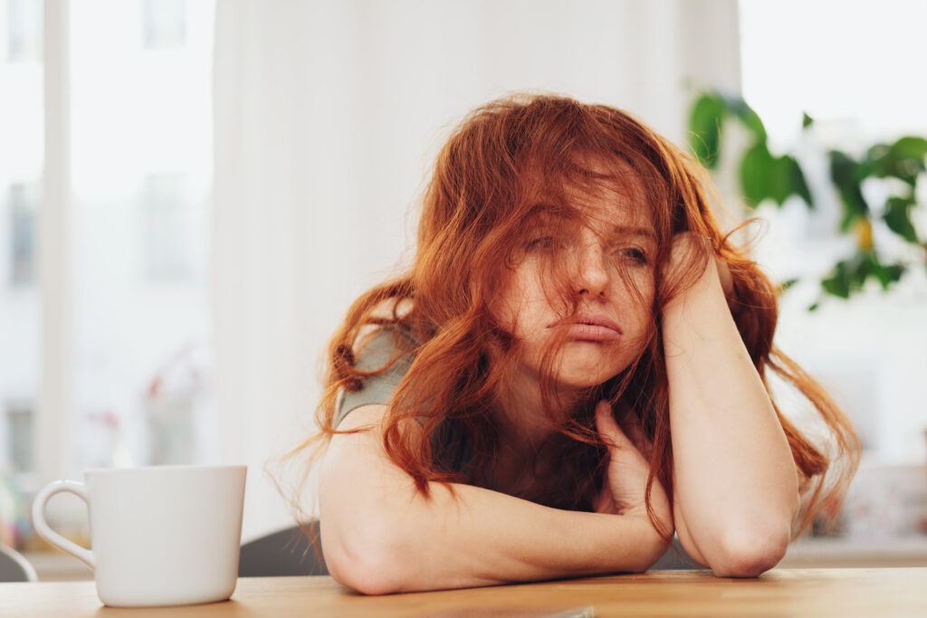 Gelangweilte Frau mit orangenen Haaren im Büro