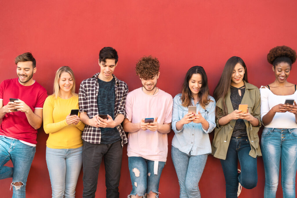 people lined up on a red wall with phones in their hands