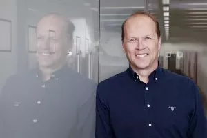 guy smiling while leaning on a glass wall